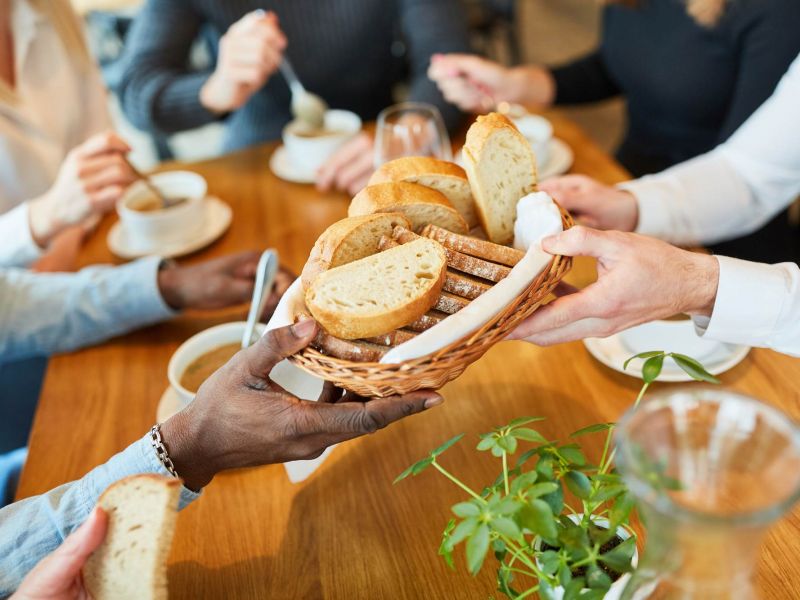Group of friends sharing fresh bread and conversation at a cozy restaurant near Linden Village.