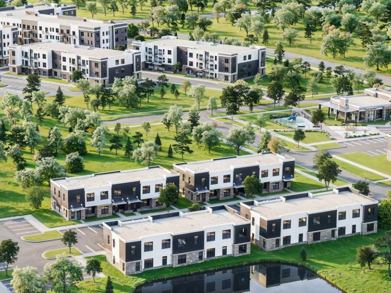 Aerial view of Linden Village showcasing modern apartment buildings, townhomes, and landscaped green spaces surrounding a central pond.