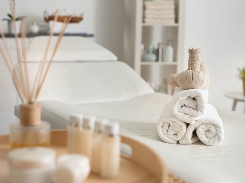 Peaceful spa setting near Linden Village with rolled towels, essential oils, and a massage bed prepared for relaxation.