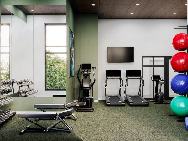 Modern fitness center at Linden Village featuring treadmills, weight equipment, and natural light from large windows.